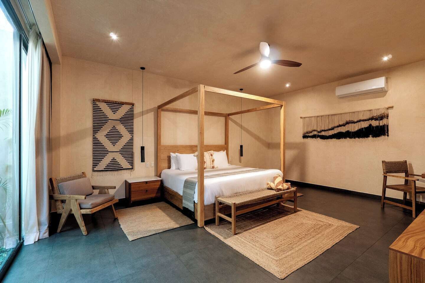 Un'ampia camera da letto con un letto a baldacchino, una ventola a soffitto e una grande finestra.