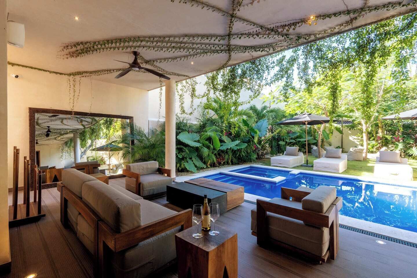 A modern outdoor living area with a pool, seating, and lush greenery.