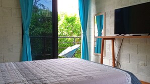 Une chambre à coucher avec un lit, des rideaux, une télévision et un balcon équipé d’une antenne parabolique.