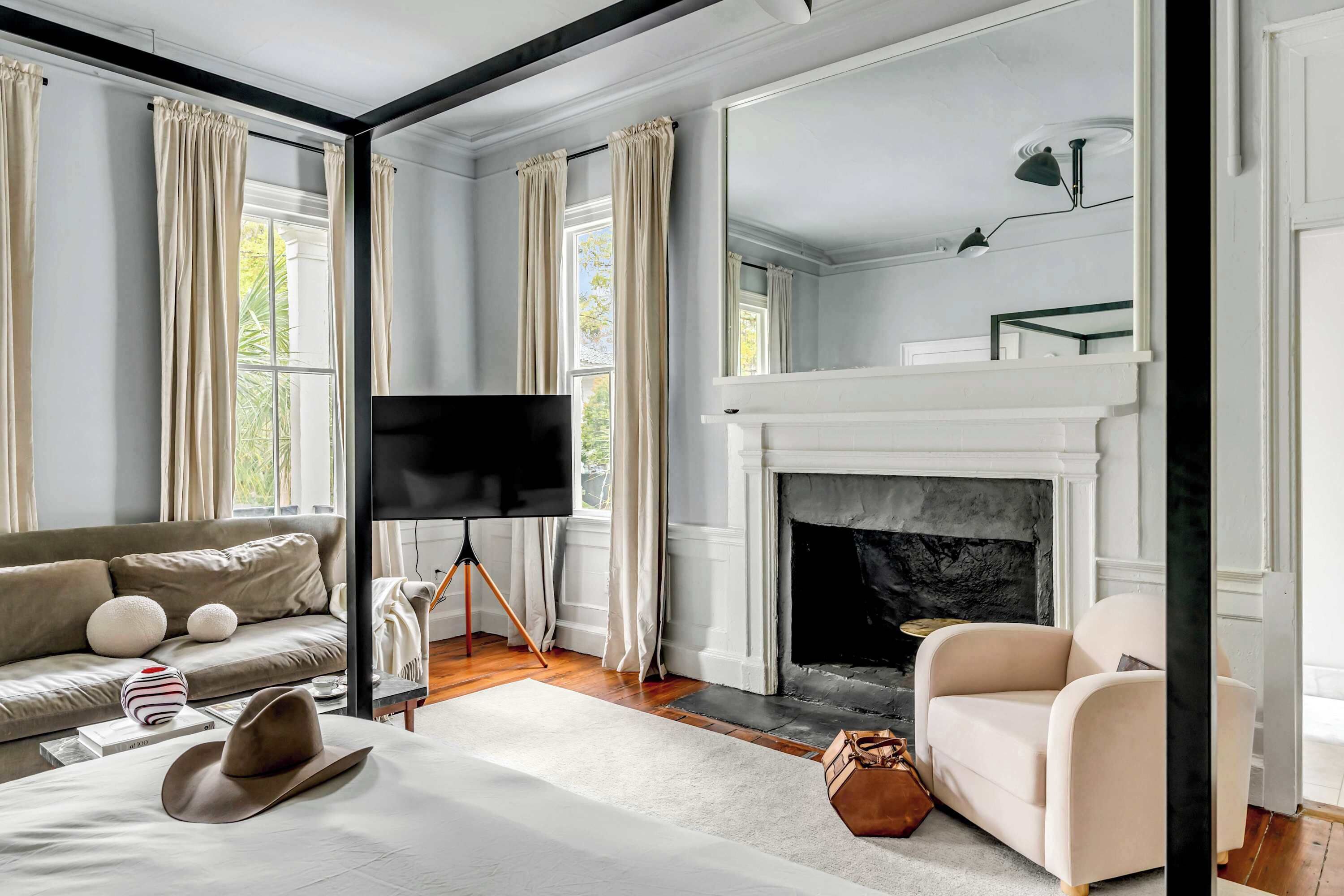 A room with a fireplace, a sofa, a TV, and a large window with curtains.