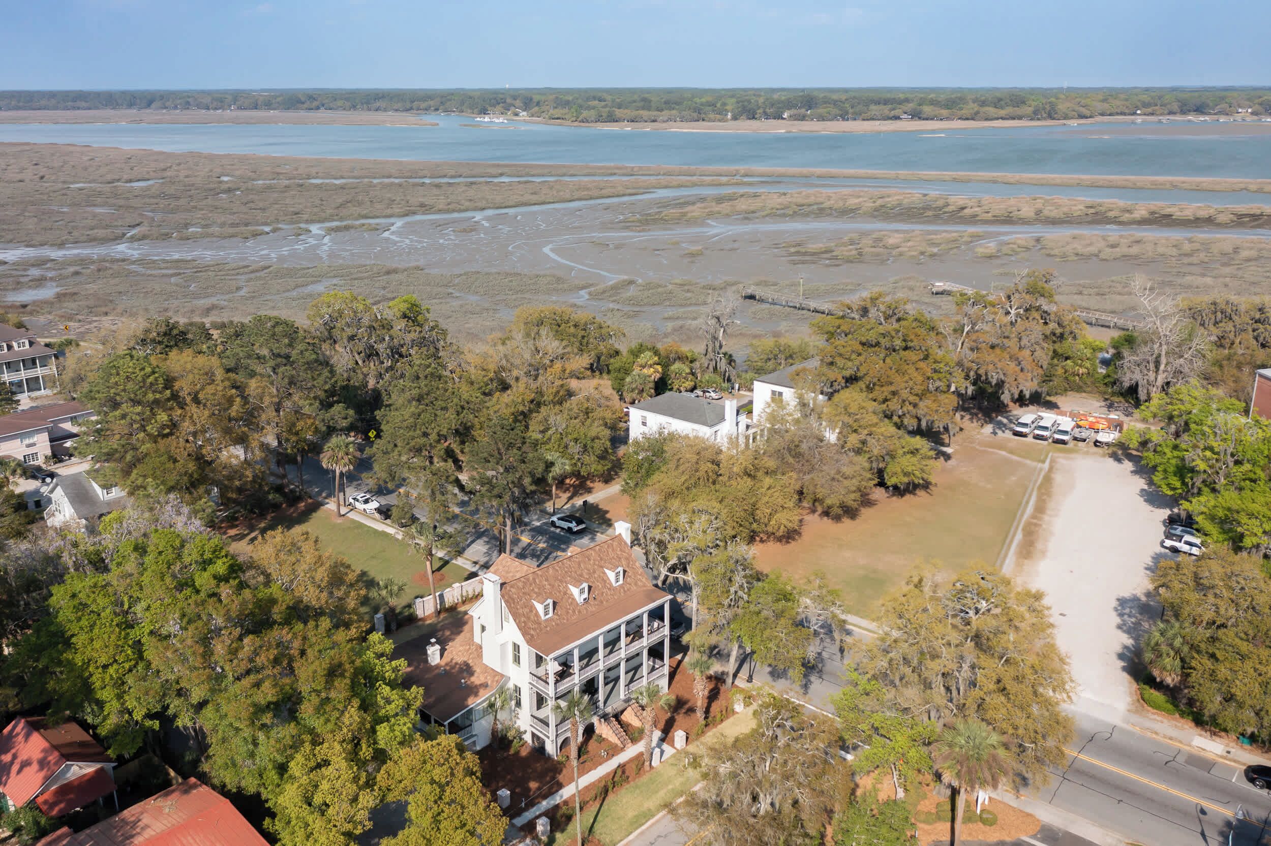 An aerial view of a coastal area with houses, a road, and a beach.