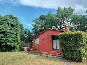 A red building with a small entrance, steps leading up to it, and a green door.