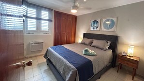 Ein Schlafzimmer mit einem Bett, einem Holzschrank, einem Deckenventilator und zwei Wanduhren.