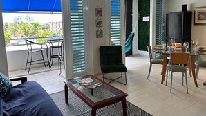 Ein modernes Wohnzimmer mit einem Glastisch, einer Couch und einem Essbereich mit Stühlen und einem für eine Mahlzeit gedeckten Tisch.