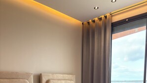 Camera d'albergo con due letti, ciascuno con testiera, un'ampia finestra con tende e vista sulla città.