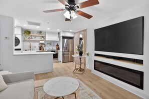 Una cocina moderna con una isla central, electrodomésticos integrados y un televisor de pantalla plana grande montado en la pared.
