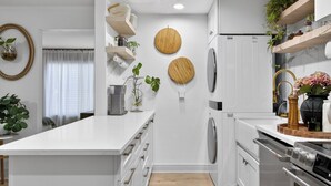 Une cuisine moderne avec des meubles blancs, un ßlot central, des appareils électroménagers intégrés et un plancher en bois.