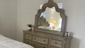 A bedroom with a bed, a dresser with drawers, a mirror, and a small potted plant. - Cozy apartment in Valrico (Valrico)