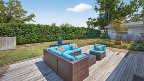 Um deck com móveis de vime e vista para o quintal.