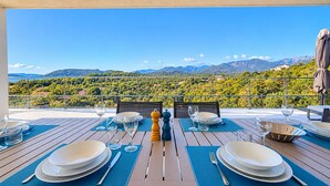 An outdoor dining area with tables set for two, overlooking a mountainous landscape. - Villa Casa Di Pinarellu (Zonza)