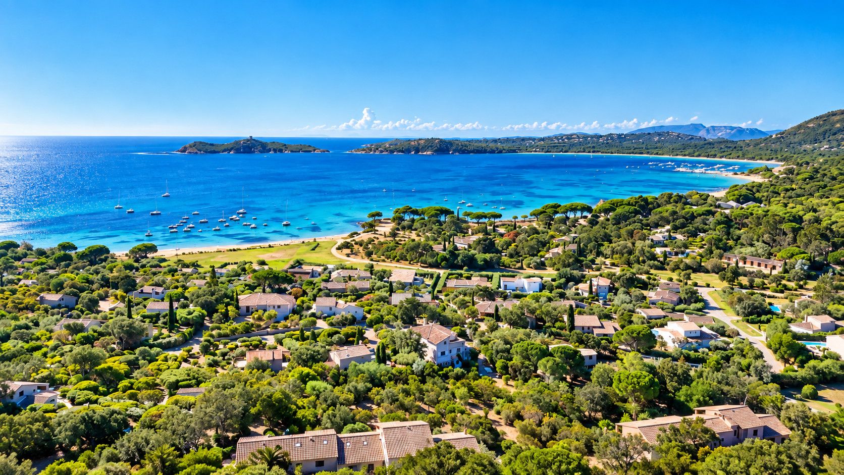 Una zona residencial costera con casas, una playa y barcos en el agua.