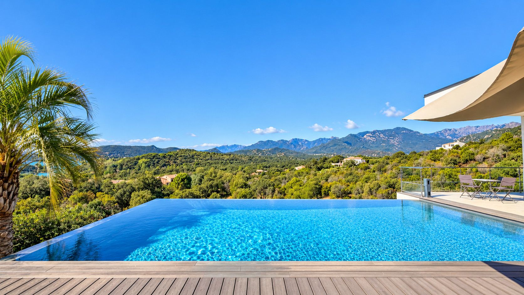 Una piscina infinita azul cristalina con un muelle de madera, rodeada de exuberante vegetaci ón y un telón de fondo montañoso.