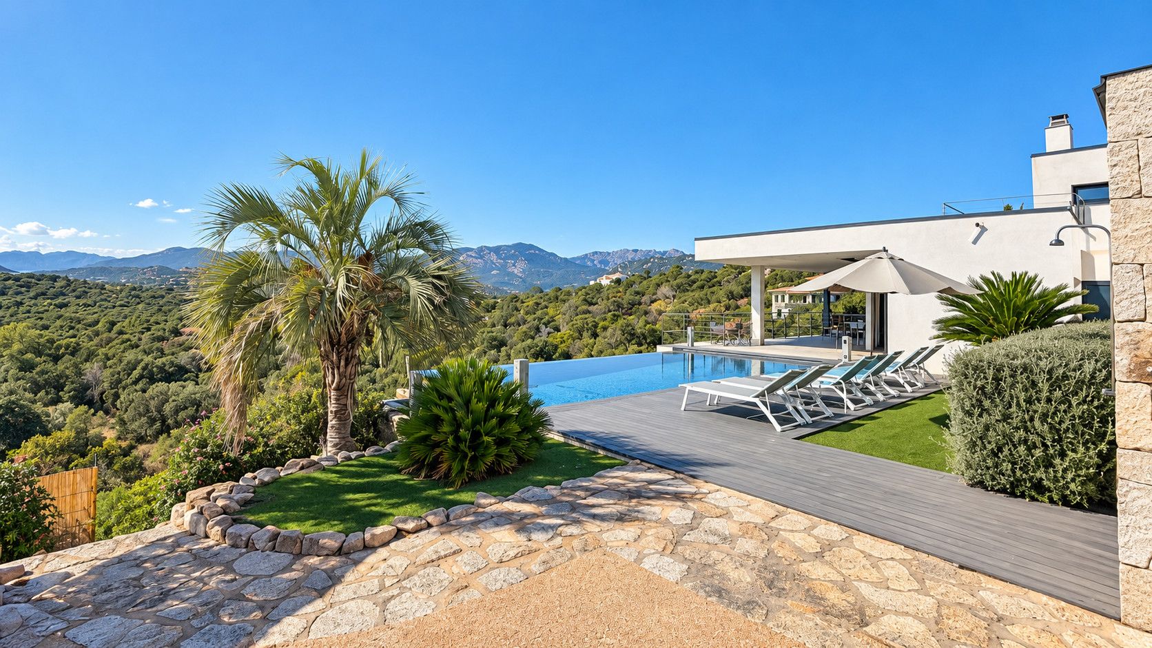 A modern villa with a swimming pool, lounge chairs, and a view of mountains.