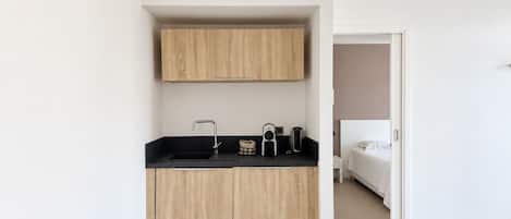 A compact kitchen with a black countertop, wooden cabinets, and a built-in vent.