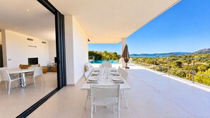 A modern dining area with a view of a pool and landscape. - Villa Roma Di Pinarellu (Zonza)