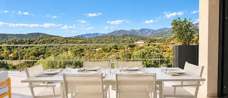 A dining area with a table set for four, overlooking a mountainous landscape.