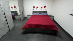 A bedroom with a large bed, a wardrobe, a nightstand, and a mirror. - Vertigo Casoria (Casoria)