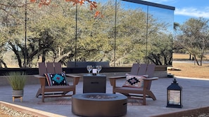 An outdoor seating area with two wooden chairs, a small table, and a fire pit.