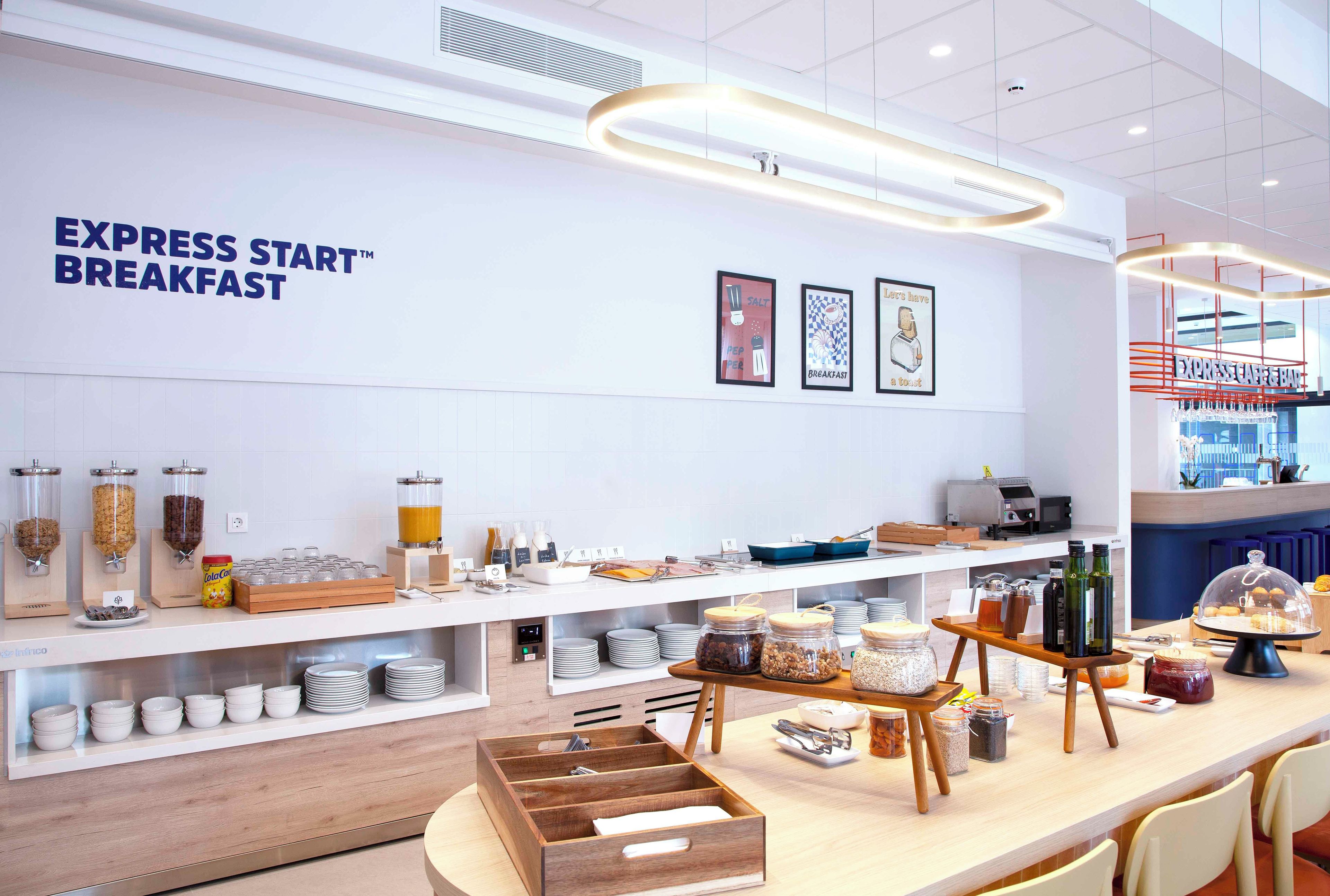 Un espace buffet pour le petit-déjeuner avec des distributeurs de nourriture clairement étiquetés, un coin café et un bar avec des places assises.