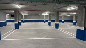Ett parkeringshus i flera våningar med betongpelare och väggar som är målade i blått och vitt.