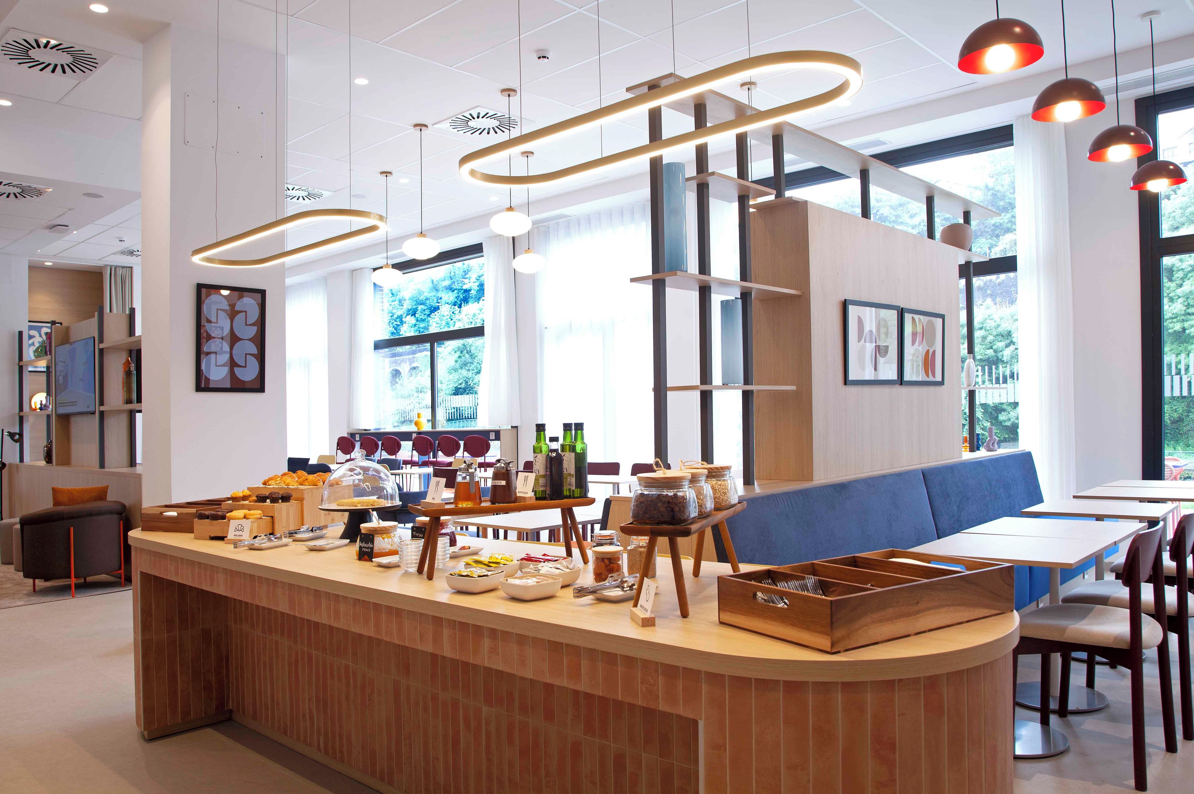 A modern cafe interior with a wooden counter, seating area, and large windows.