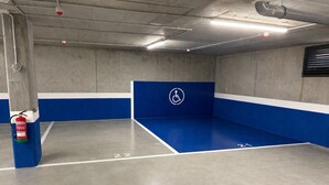 Un estacionamiento con paredes pintadas de azul y blanco, un extintor montado en un pilar y un símbolo de accesibilidad para sillas de ruedas en la pared.