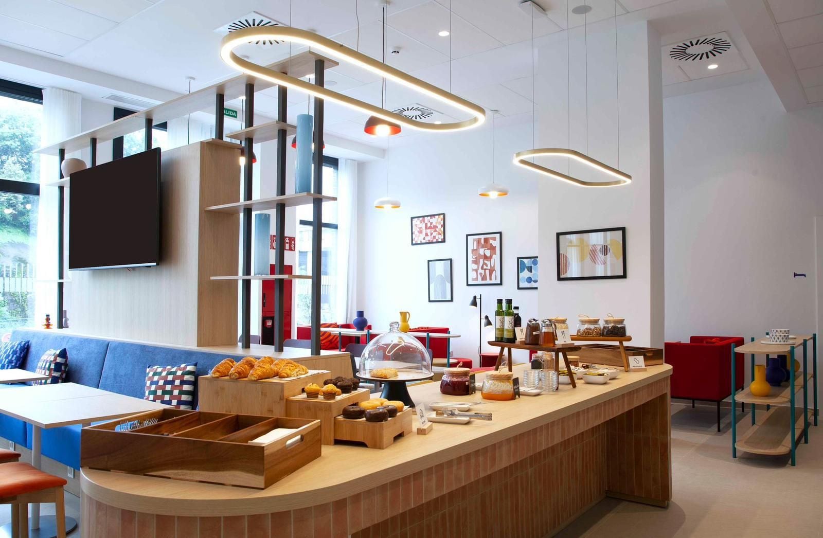 Un café moderne avec un comptoir en bois, un espace salon et des œuvres d’art accrochées aux murs.