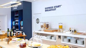 Un bufé de desayuno con diversas opciones de comida, salsas y un reloj en la pared.