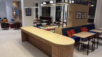 Un interior moderno con un mostrador central de madera, zonas de estar e iluminación colgante.
