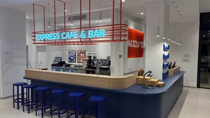 Ein modernes Café und eine Bar mit einer Neonreklame, Barhocker, einer Kaffeemaschine und einer Theke mit einem Computer.