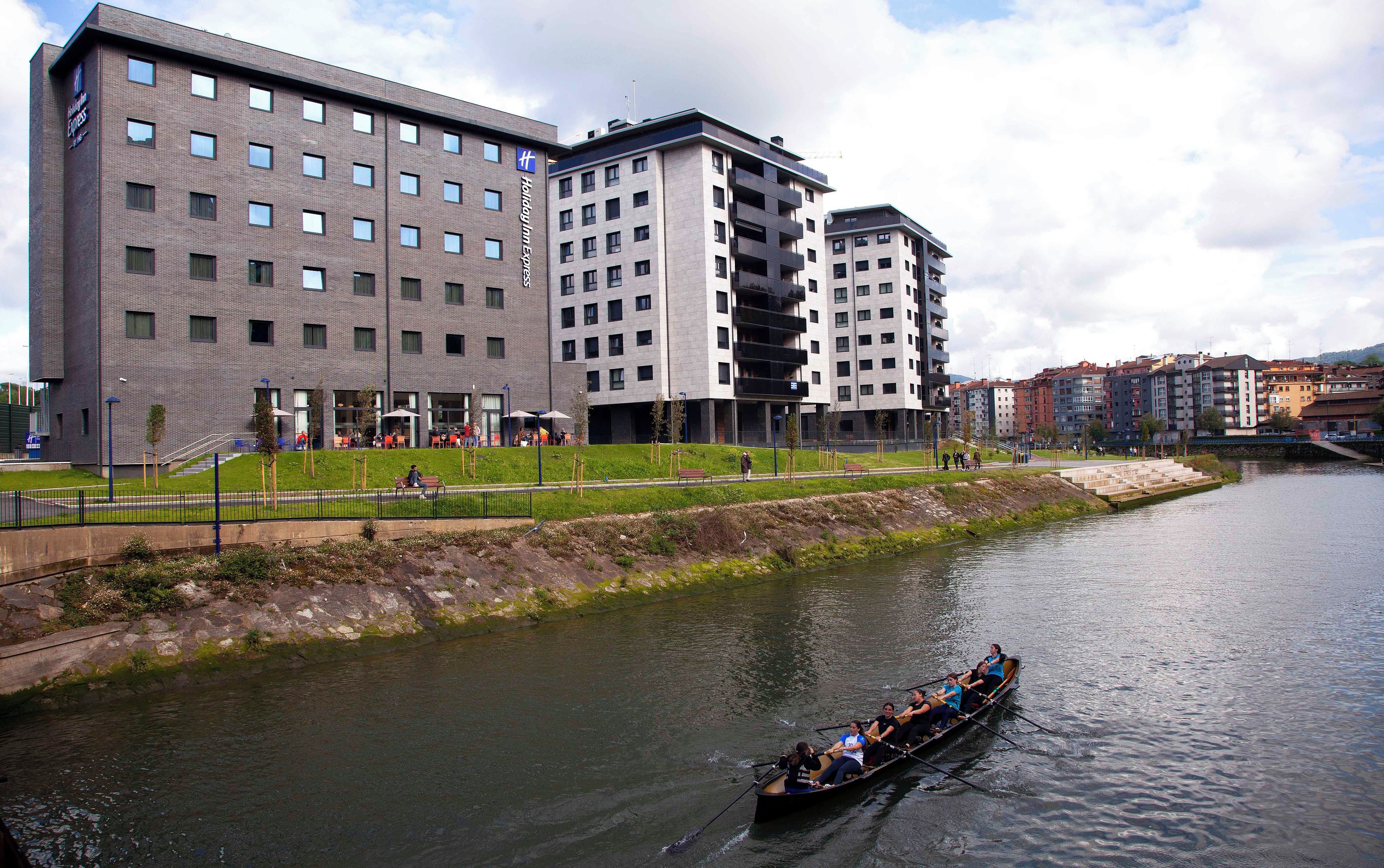 Un hôtel moderne à plusieurs étages, doté d’une terrasse et situé en bord de rivière.