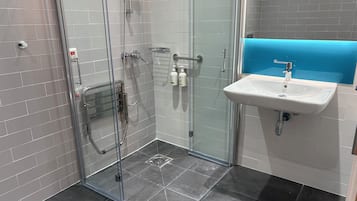 Un bagno moderno con box doccia in vetro, lavandino bianco e parete decorata in blu.
