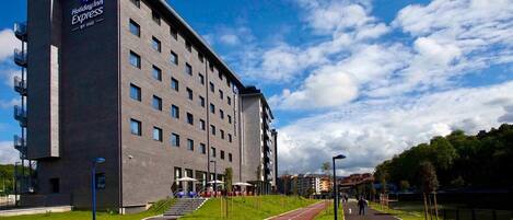 A Holiday Inn Express hotel with a modern brick facade, a central entrance, and a surrounding green space.