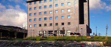 A modern building with a flat roof, multiple windows, and a sign indicating it's a hotel.