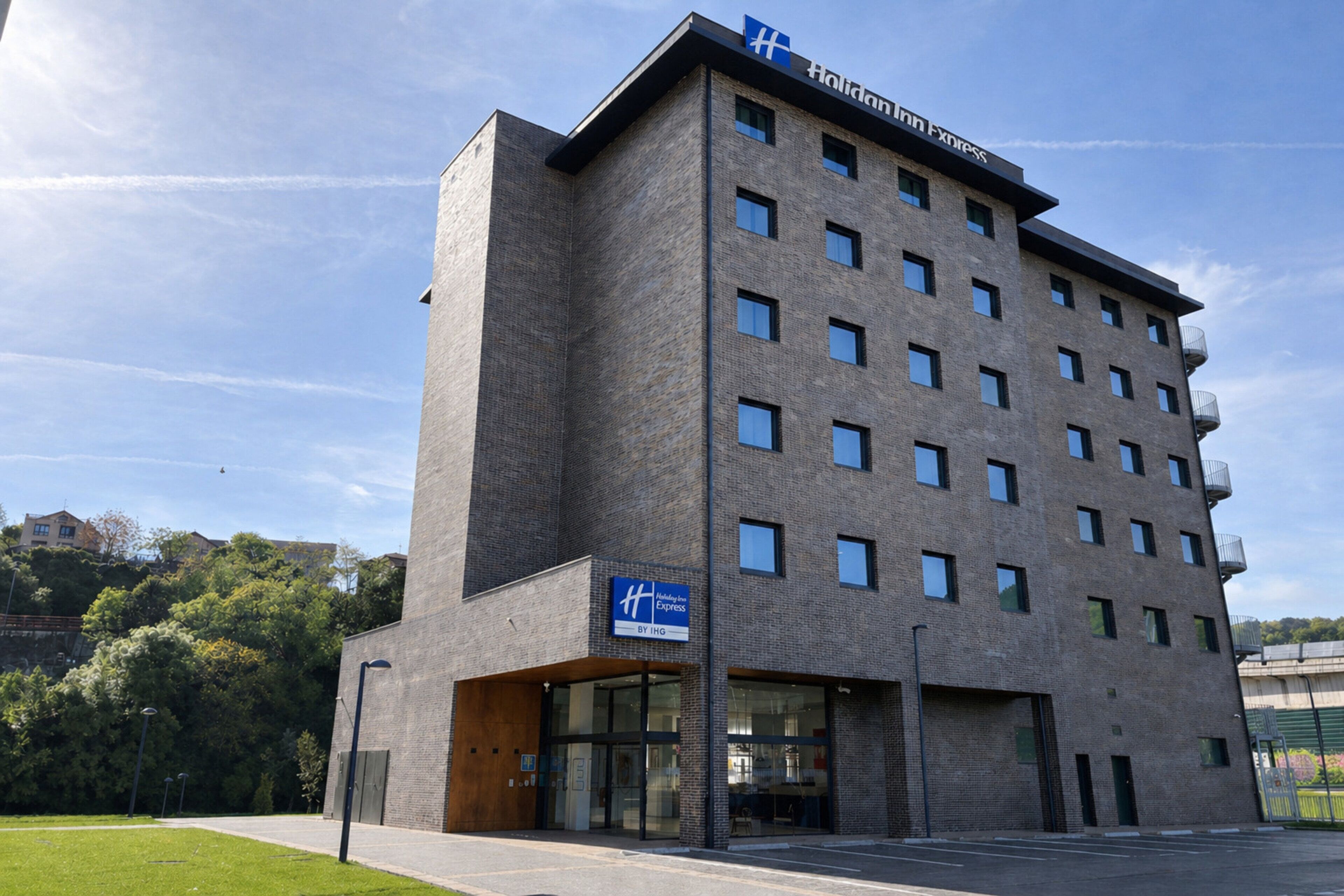 A modern hotel building with a flat roof, multiple windows, and a sign indicating it is a Holiday Inn Express.