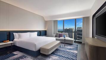 Una habitación de hotel moderna con una cama grande, un sofá, una mesita y un televisor.