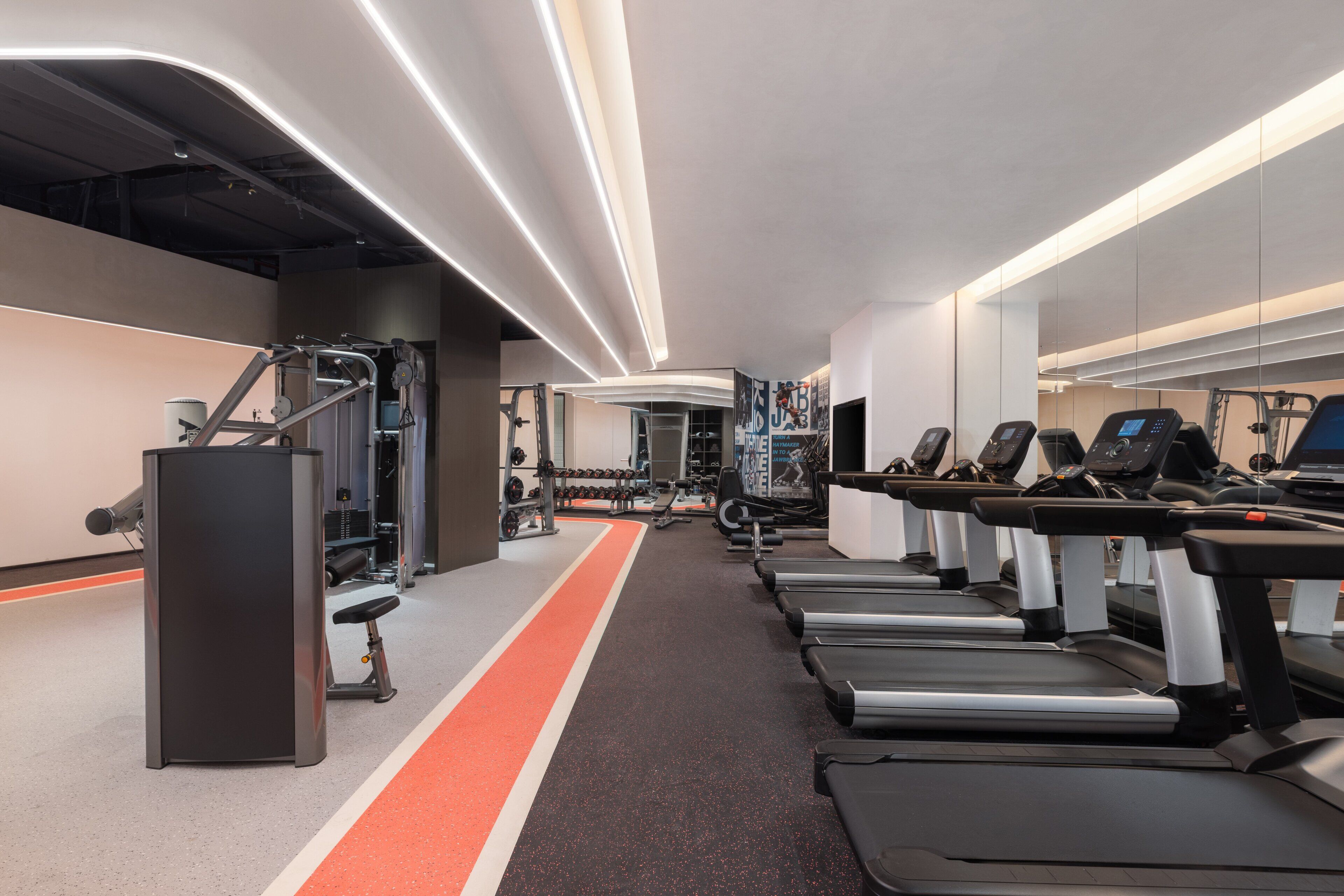 A modern gym with treadmills, weight machines, and a running track.