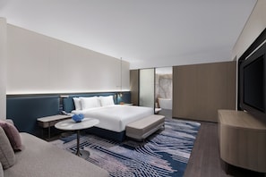 A modern hotel room with a large bed, a small round table, a sofa, a TV, and a bathroom visible through a glass partition. - Crowne Plaza Suzhou Taihu Lake By Ihg (Suzhou)