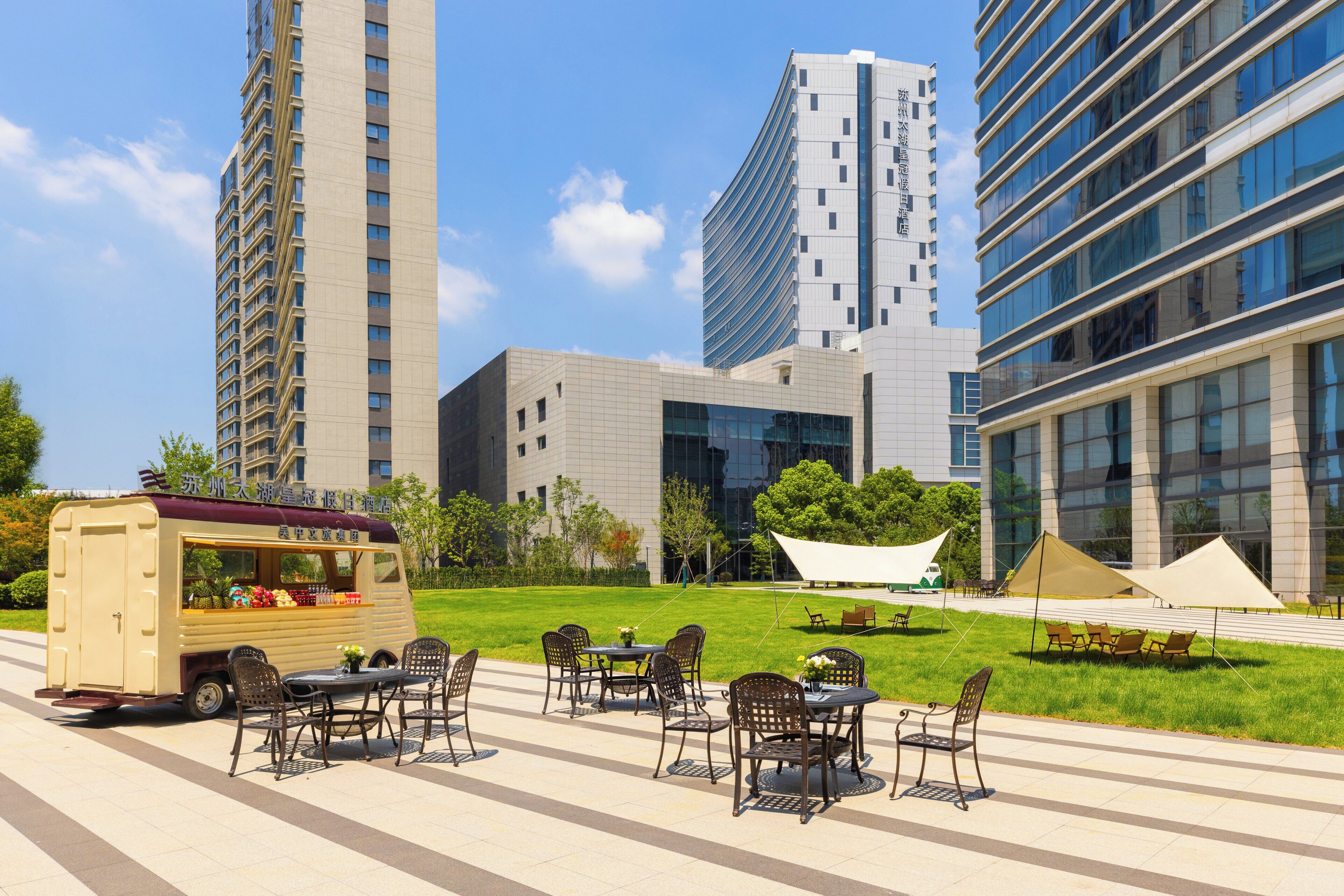 A food truck with outdoor seating in a plaza with modern buildings in the background.