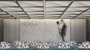 A banquet hall with a large screen displaying a couple kissing, a row of round tables with white tablecloths and blue sashes, and a patterned ceiling. - Crowne Plaza Suzhou Taihu Lake By Ihg (Suzhou)
