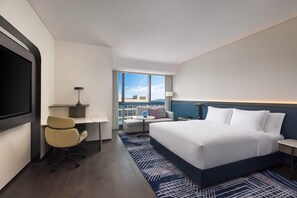 A hotel room with a large bed, a desk, a chair, a TV, a lamp, and a view of the city. - Crowne Plaza Suzhou Taihu Lake By Ihg (Suzhou)