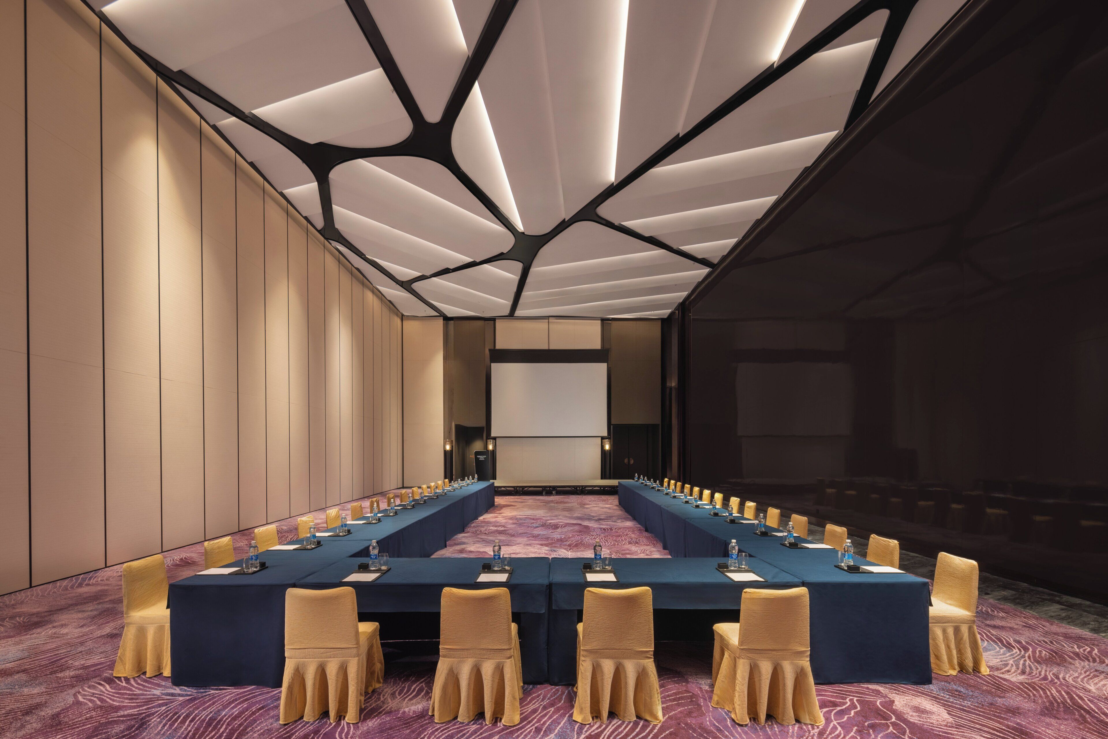 A conference room with a long table, chairs, and a modern ceiling design.