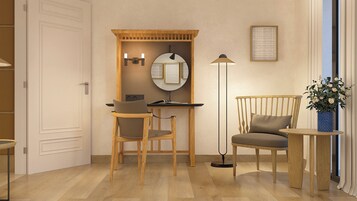 A room with a desk, two chairs, a floor lamp, a mirror, and a vase with flowers.