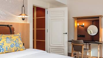 Une chambre d’hôtel comprenant un lit, un bureau, une chaise, une armoire et un miroir.