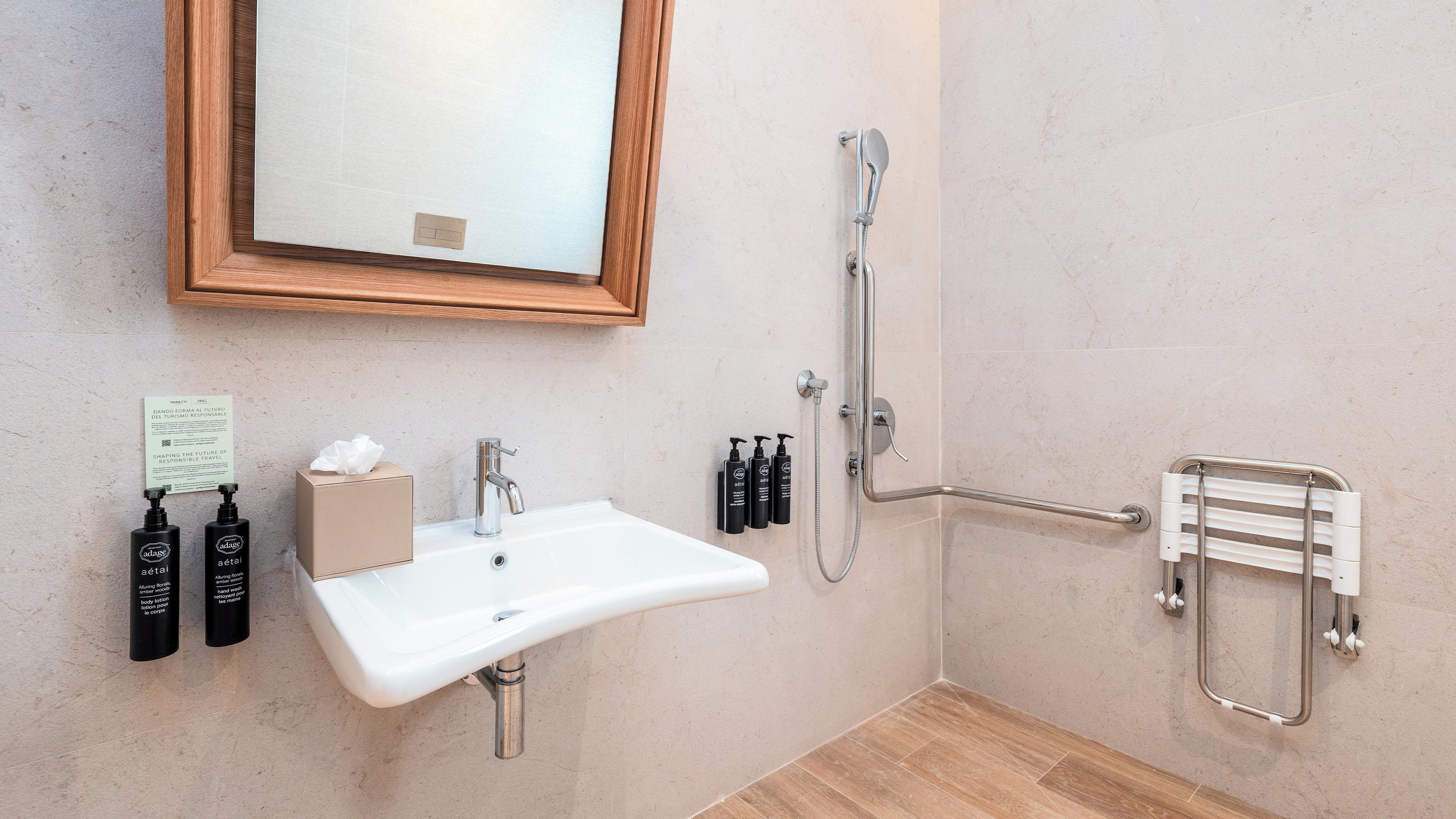 Ein Badezimmer mit Waschbecken, Spiegel, Duschbrause und Haltestange.
