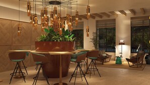 A modern lounge area with a central wooden planter, bar stools, and hanging pendant lights. - Casa Del Compositor, Vignette Collection by IHG (Jerez de la Frontera)