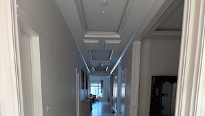 En gang med marmorgulv, hvide vægge og et loft med indbygget belysning.