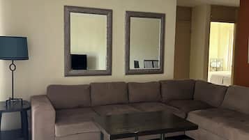 A living room with a brown sofa, a small table, two wall mirrors, a lamp, and a ceiling light.