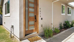 A modern house with a wooden front door, a number '4619' on the wall, and a small garden with plants and a doormat. - Spacious and private 1-bedroom guesthouse, located near UC Davis Health (Sacramento)