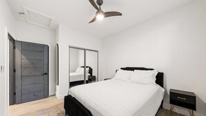 A modern bedroom with a large bed, a ceiling fan, a wardrobe, and a bedside table. - Spacious and private 1-bedroom guesthouse, located near UC Davis Health (Sacramento)